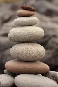 Pilhas de pedras lisas equilibradas ao pôr do sol representando harmonia entre chief financial controller