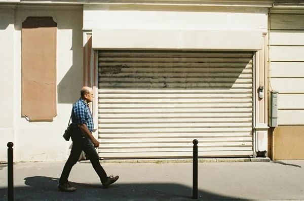 Fachada branca comércio homem caminhando representando precificação de produtos