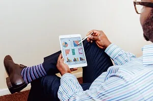Profissional analisando tablet com gráficos analista de controladoria o que faz